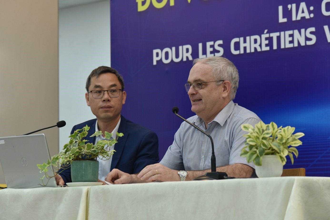 A couple of men sitting at a table with microphones Description automatically generated