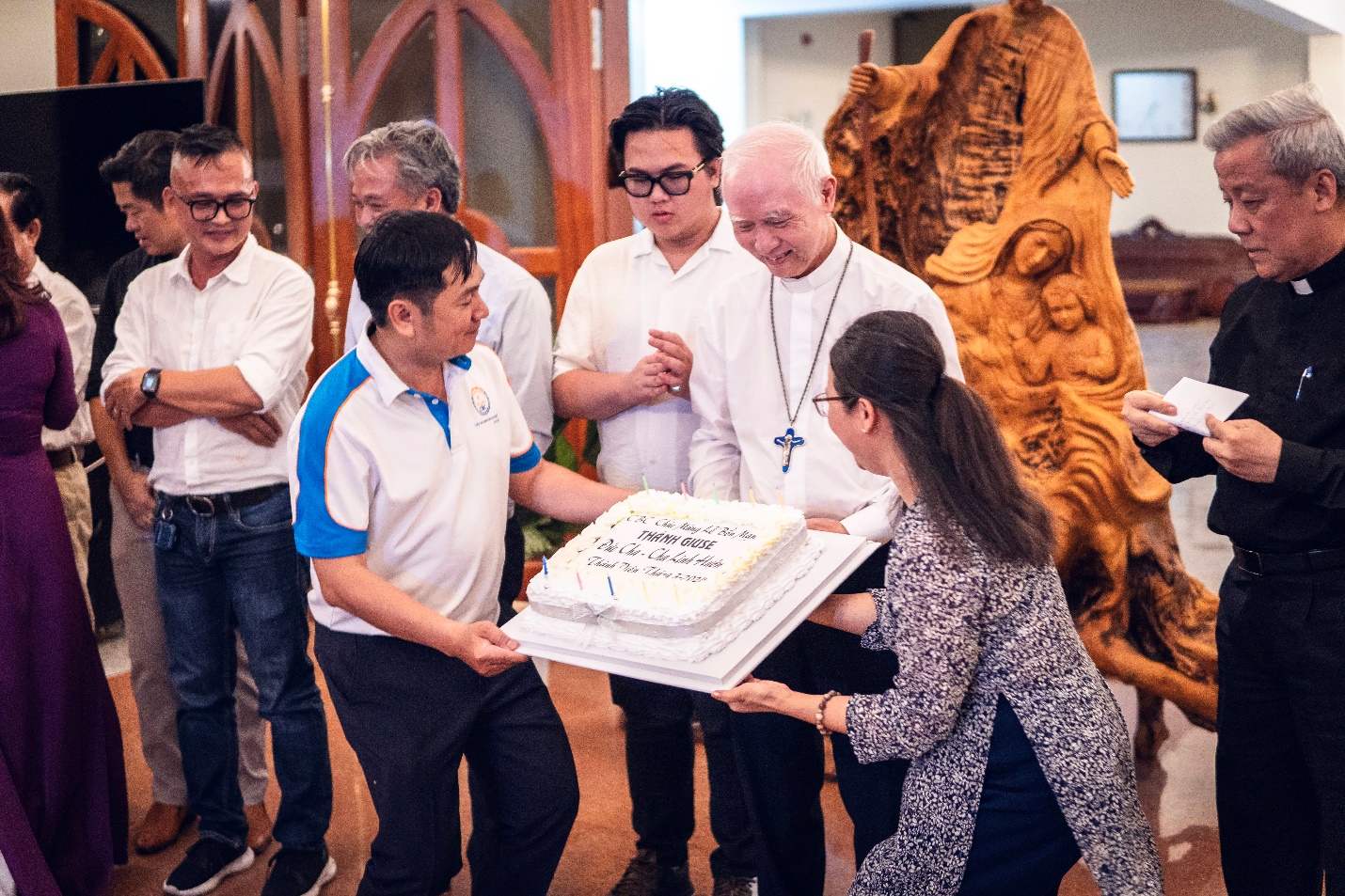 A group of people holding a cake Description automatically generated
